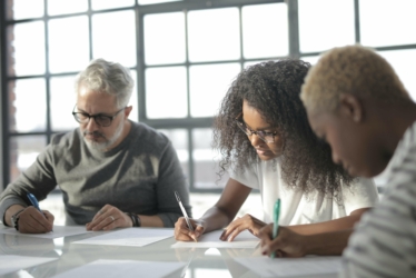 Students of various ages writing at a table